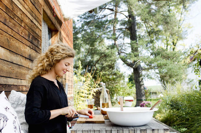 Junge Frau hackt Gemüse am Tisch im Freien — Stockfoto