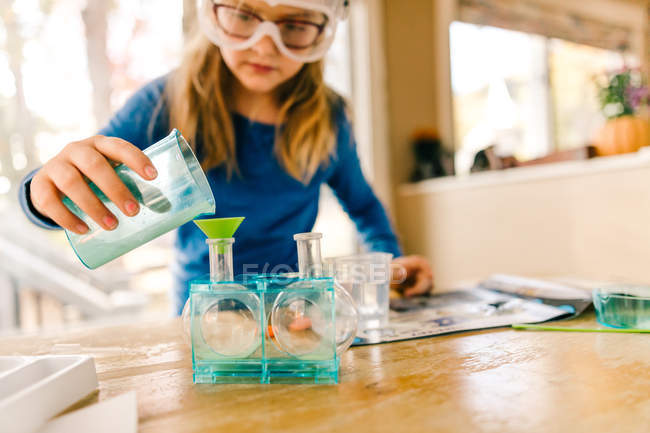 Chica haciendo experimento científico, vertiendo líquido en el frasco - foto de stock
