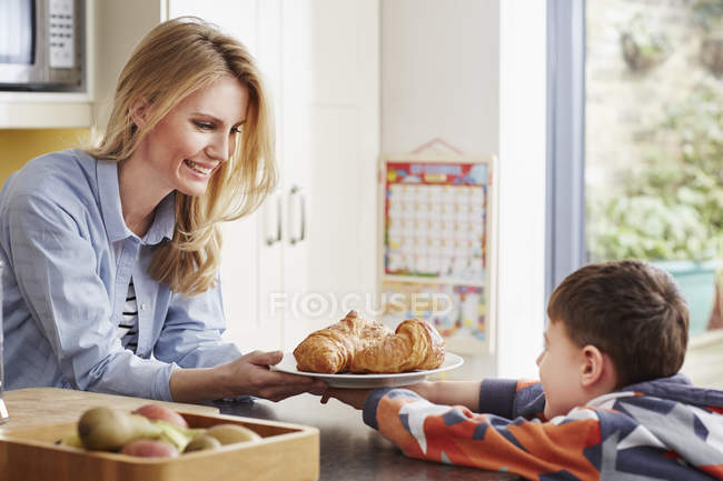 Mère donnant croissant fils — Photo de stock