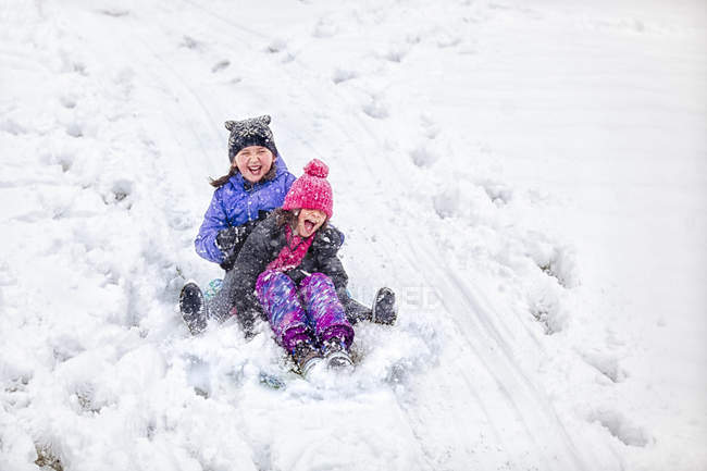 Friends tobogganing downhill in winter — Stock Photo