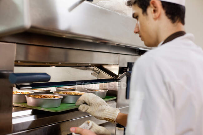 Bäcker stellt Essen in Backofen in Küche — Stockfoto