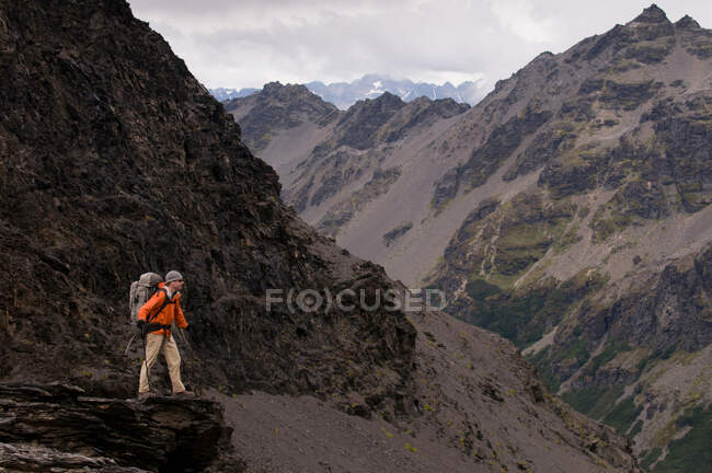 Hiker walking with sticks in rocky hills — Stock Photo