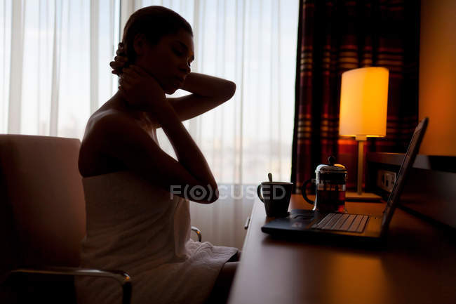 Jovem mulher sentada no laptop no quarto de hotel — Fotografia de Stock