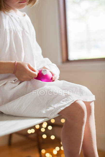 Girl on table playing with Christmas decorations — Stock Photo