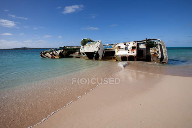 Shipwreck on sandy shore in bright sunlight — Stock Photo