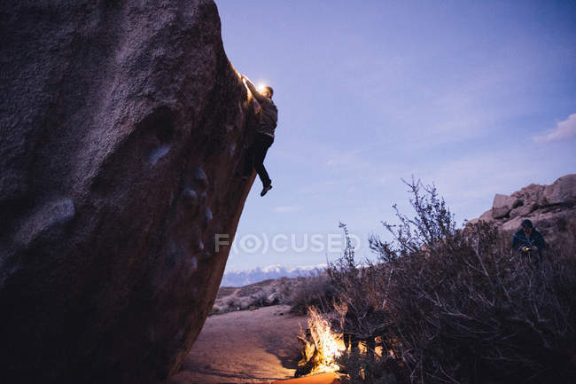 Amigos escalada en roca por la noche, Buttermilk Boulders, Bishop, California, EE.UU. - foto de stock