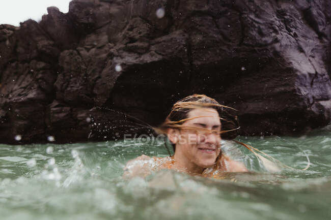 Mujer en mar sacudiendo la cabeza, salpicaduras, Oahu, Hawaii, EE.UU. - foto de stock