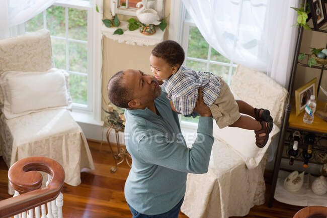 A grandfather lifting his grandson in the air — Stock Photo