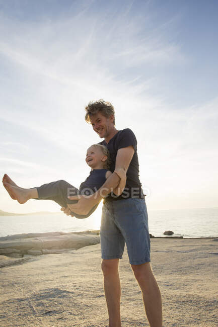 Reifer Mann schwingt seine Kleinkind-Tochter am Strand von Calvi, Korsika, Frankreich — Stockfoto