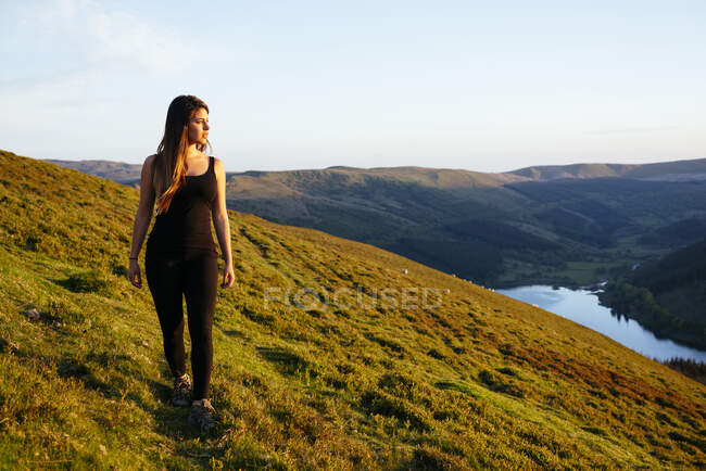 Mujer joven paseando, embalse de Talybont en el valle de Glyn Collwn, Brecon Beacons, Powys, Gales - foto de stock