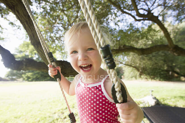 Retrato de una niña en el columpio del árbol - foto de stock