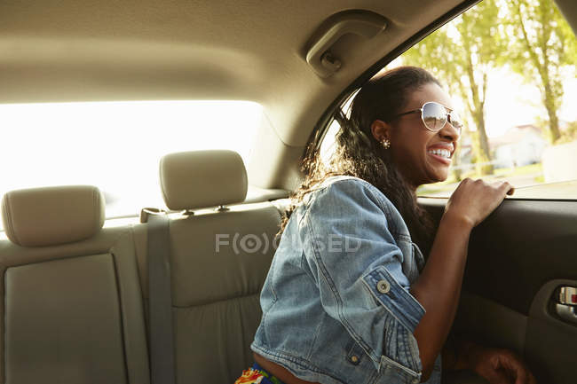Jeune femme portant des lunettes de soleil regardant par la fenêtre de la voiture — Photo de stock
