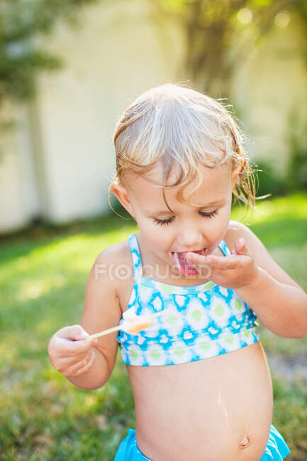 Fille avec les cheveux mouillés tenant glace laineux et lécher les doigts — Photo de stock