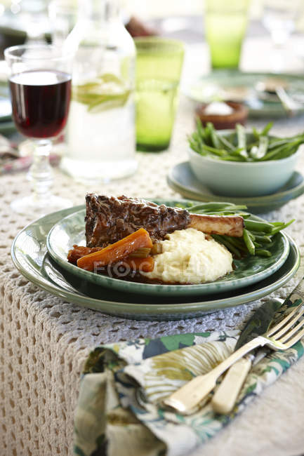 Plate of lamb shank stew with carrots, green beans and mashed potatoes — Stock Photo