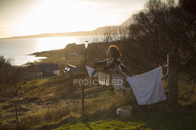 Mujer colgando lavando en el jardín, Tokavaig, Isla de Skye, Escocia - foto de stock