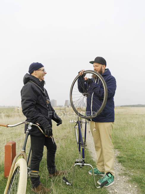 Urban cyclists fixing tyre in field — Stock Photo
