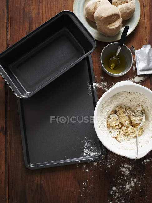 Top view of baking trays and bread mixture in mixing bowl — Stock Photo