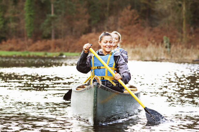 Жінки веслують на каное на все ще озері — стокове фото