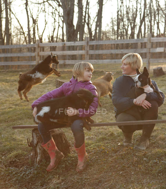 Мати і дочка на відкритому повітрі, обіймаючи кіз і собаку — стокове фото