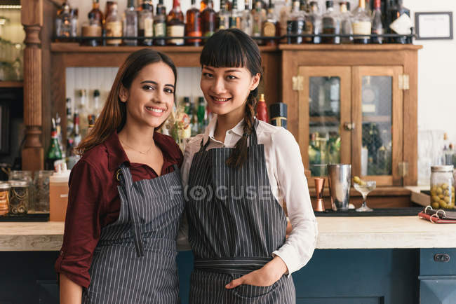 Portrait of two young female bartenders in cocktail bar — Stock Photo