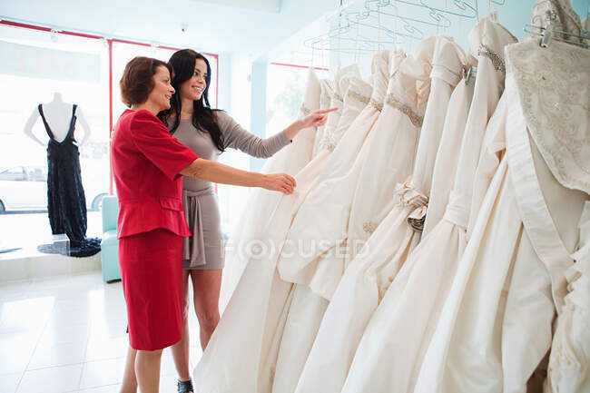 Мати і дочка дивлячись на весільні сукні — стокове фото