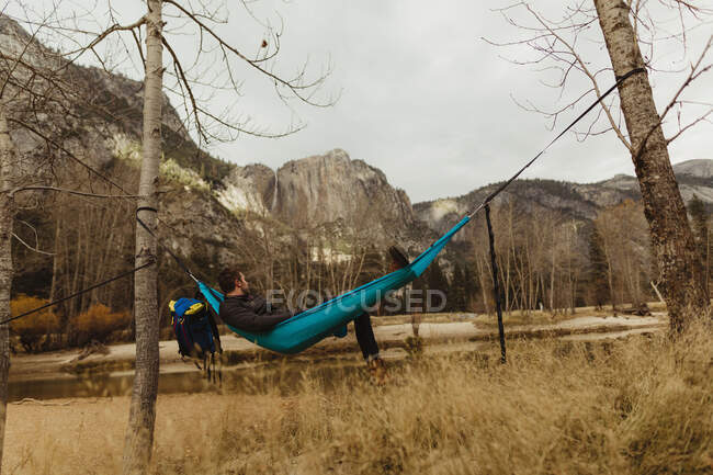Mann liegt in Hängematte und blickt auf Landschaft, Yosemite National Park, Kalifornien, USA — Stockfoto
