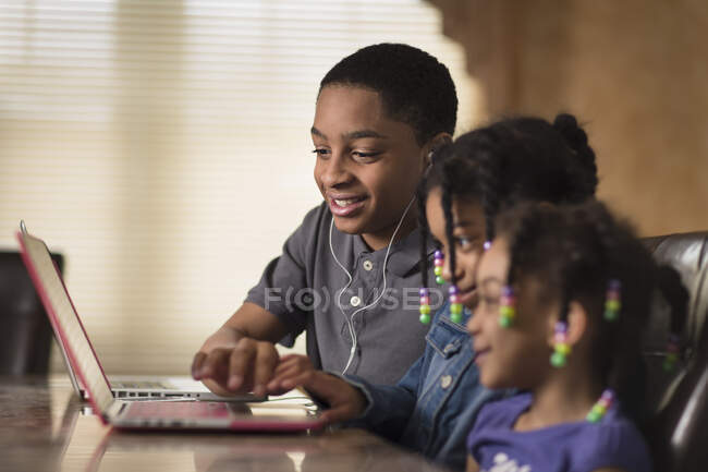 Мальчик и девочка дома работают с ноутбуками, выполняя домашнюю работу — стоковое фото