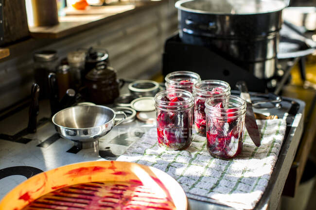 Preserves jars of beetroot on tea towel in kitchen — Stock Photo