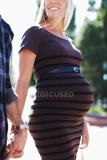 Обрізаний знімок вагітної середньої дорослої жінки, що тримає руки з хлопцем — стокове фото