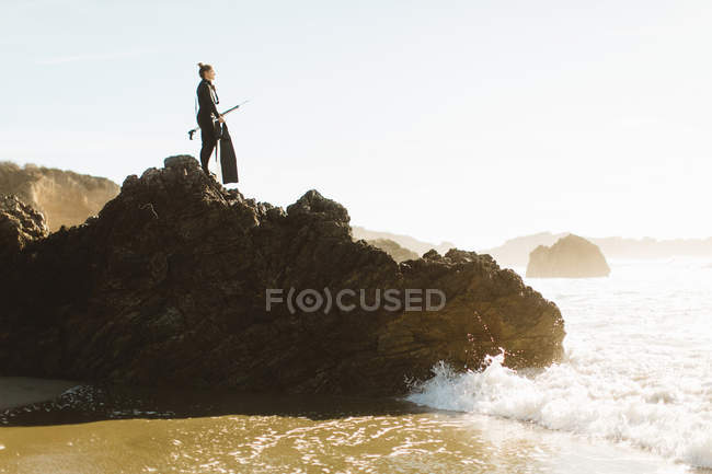 Дайвер с копьем, стоящий на скале, Биг-Сур, Калифорния, США — стоковое фото