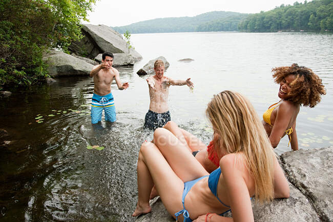 Men splashing friends at lake — Stock Photo