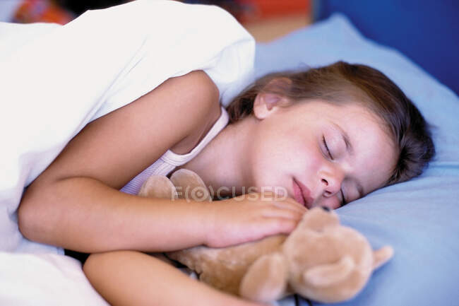 Chica durmiendo con osito de peluche - foto de stock