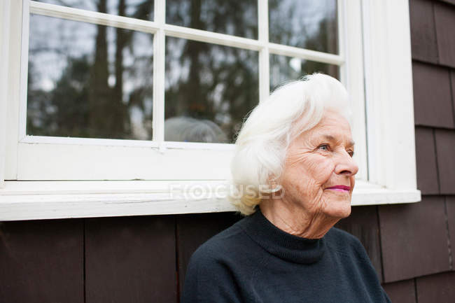 Retrato de mulher idosa fora de casa olhando para longe — Fotografia de Stock