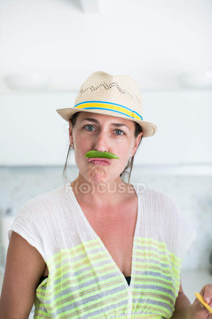 Portrait of adult woman in straw hat and pea pod moustache — Stock Photo