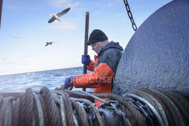 Fisherman preparing net on trawler — Stock Photo