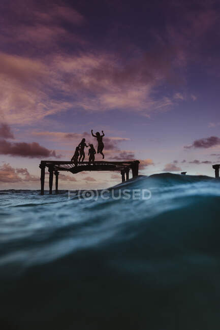 Silueta de amigos rebotando en el trampolín en el mar, Oahu, Hawaii, EE.UU. - foto de stock