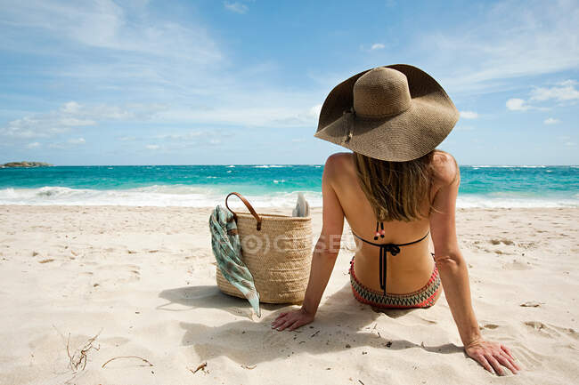 Mujer sentada en la playa de arena, Mustique, Islas Granadinas - foto de stock