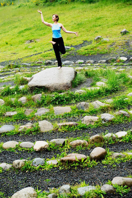 Donna in posa yoga su pietra nel labirinto — Foto stock