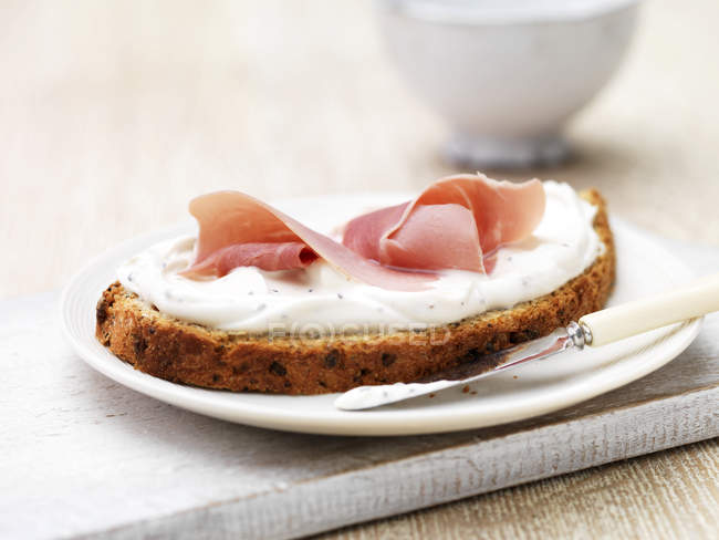 Soft cheese and ham on sliced wholemeal bread with butter knife — Stock Photo