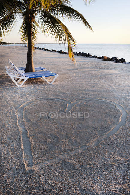 Шезлонги біля форми серця на піщаній поверхні пляжу — стокове фото