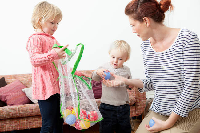 Madre e bambini che giocano con le palle di plastica — Foto stock
