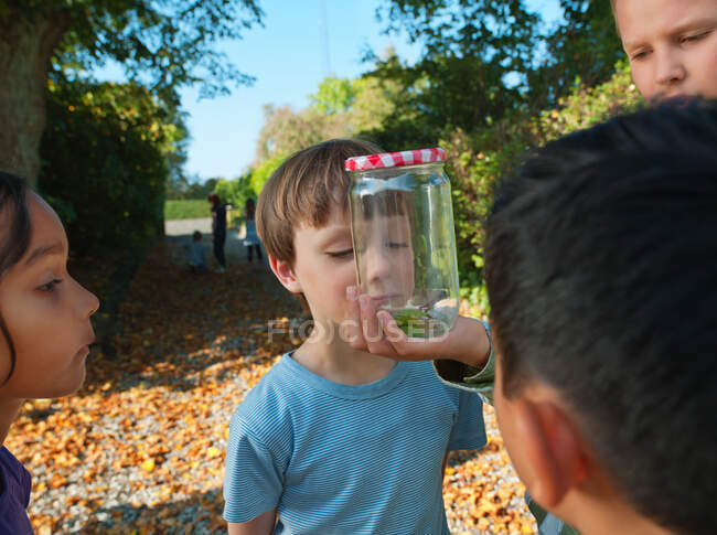 Junge zeigt Kindern Glas — Stockfoto