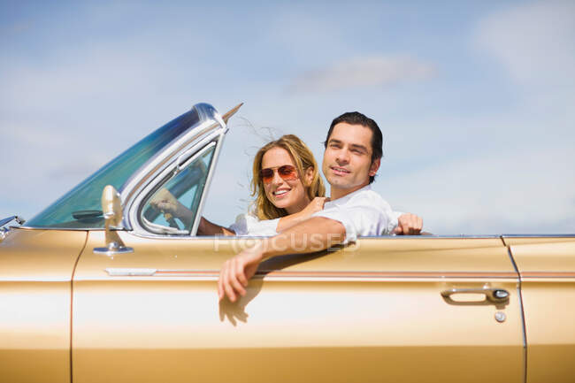 Молодая пара за рулем кабриолета — стоковое фото