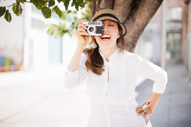 Mulher adulta média usando câmera vintage, sorrindo — Fotografia de Stock