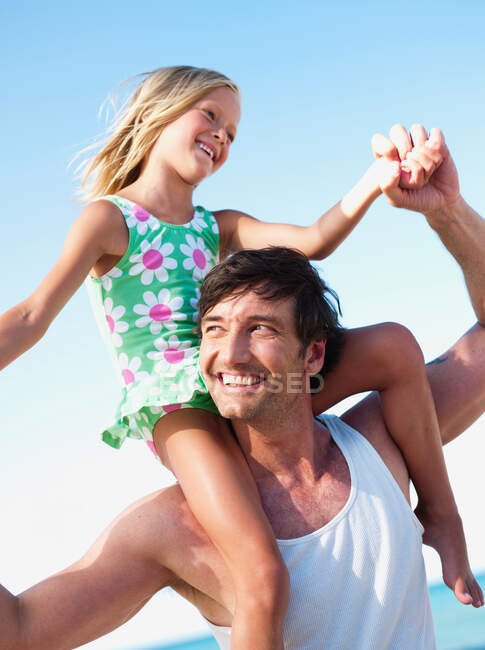 Hija y padre jugando en la playa - foto de stock
