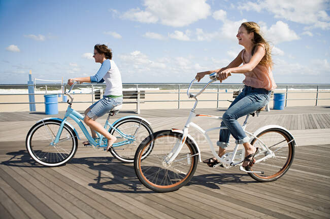 Two women cycling on boardwalk — Stock Photo