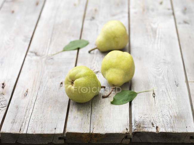 Three pears and leaves on wooden table — Stock Photo