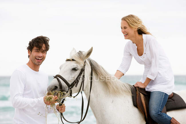 Uomo e donna con cavallo sulla spiaggia — Foto stock