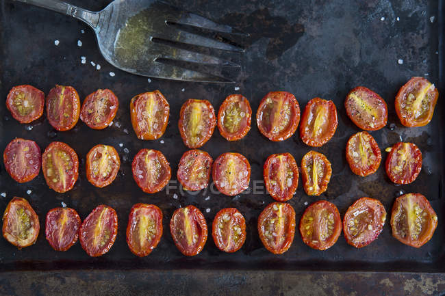 Top view of rows of halved roasted tomatoes on baking tin — Stock Photo