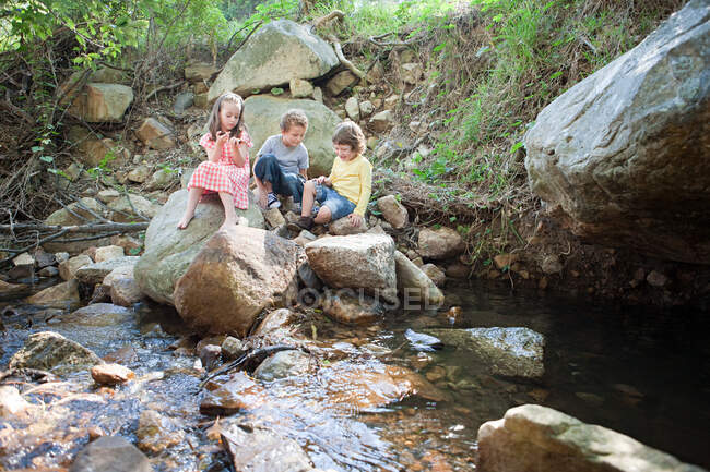 Niños en las rocas por el río - foto de stock